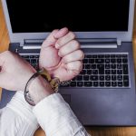 men s hands handcuffed on a laptop cybersecurity law concept